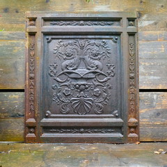  Antique cast iron wall sculpture with a classic floral motif on a weathered wooden wall