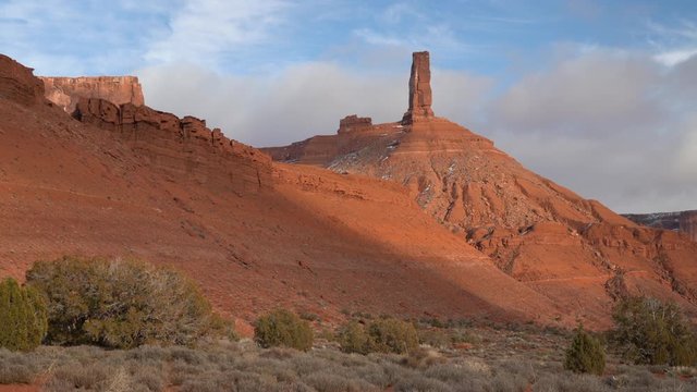 Pan along sandstone rock formation in Castle Valley near Moab, Utah with iconic Castleton Tower, winter scenery with some snow. The Tower is world-renowned as a subject for photography and for its cla