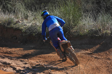Zoom photo of mud track enduro motocross rider performing freestyle stunts in high speed