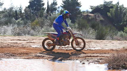 Zoom photo of mud track enduro motocross rider performing freestyle stunts in high speed