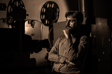 man standing near a film projector in the room projectionist