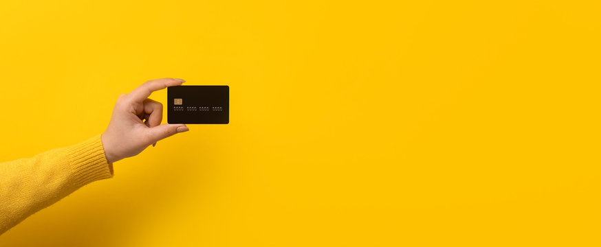 bank card in hand over yellow background, panoramic mock-up