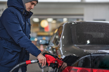 Close-up of a man pumping gasoline into a car at a gas station.