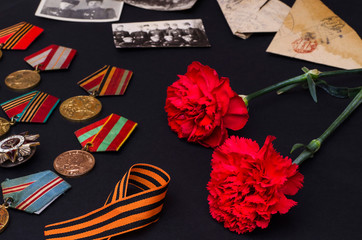 Victory Day. Carnations on a black background with old military letters, photographs, St. George...