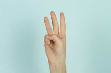 Three fingers displayed by a human hand isolated on a blue background.