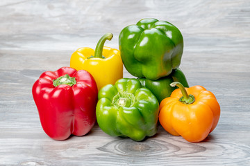 Green orange and red bell peppers on a wood tabletop
