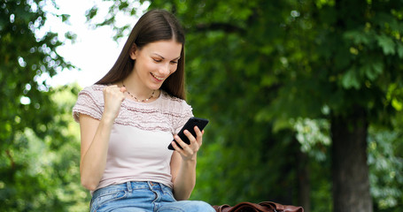 Very happy woman reading good news via her smartphone - victory concept