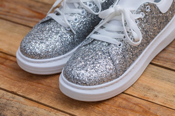 Glittery sneakers on wood background, close-up