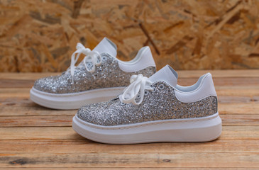 Glittery sneakers on wood background, close-up