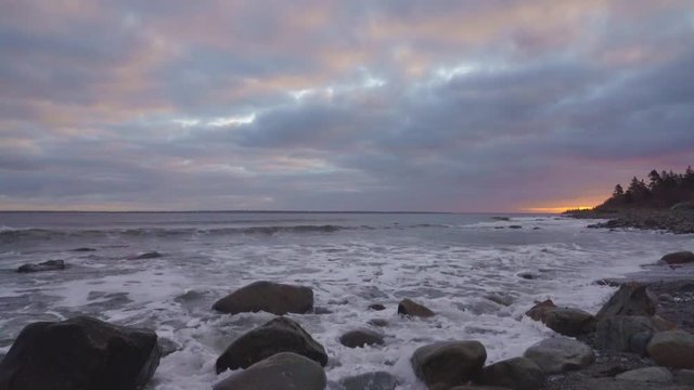 Beautiful morning at the rocky beach with gorgeous clouds and a glow in the sky
