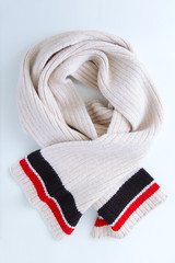 Woolen beige scarf with colored stripes around the edge. Winter clothes.