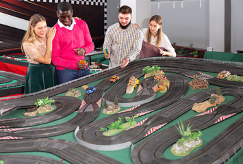 Two teams from couples play slot car racing game