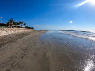 A sunny day on Seminyak Beach on Bali, Indonesia. There is a small Balinese temple on the side of the beach. Waves gently washing the shore. Clear and sunny day.
