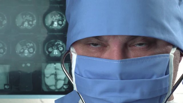 Doctor in protective medical mask listening to heartbeat and lung function  using stethoscope in clinic. Close up View. 