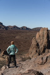 Woman in bright blue jacket  the beautiful volcanic valley with mountains on the background during. Winter traveling on Tenerife island, Spain