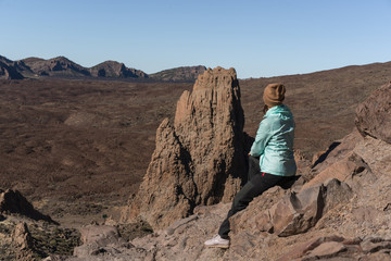 Naklejka premium Woman in bright blue jacket the beautiful volcanic valley with mountains on the background during. Winter traveling on Tenerife island, Spain