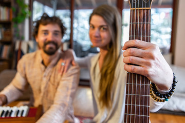 Closeup of shamanic woman holding classical guitar with man playing musical instrument harmonium as...