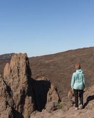 Naklejka premium Woman in bright blue jacket the beautiful volcanic valley with mountains on the background during. Winter traveling on Tenerife island, Spain