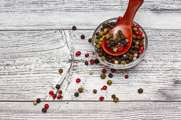 A mixture of peppers in a glass bowl in a wooden spoon