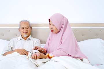 Muslim woman measuring her husband blood pressure