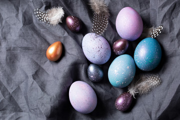 Easter. Festive bright eggs in a wooden bowl on a background of gray cotton fabric. Top view.