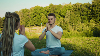 Close-up caucasian couple take a rest in the park practising yoga poses deep breathing cardio...