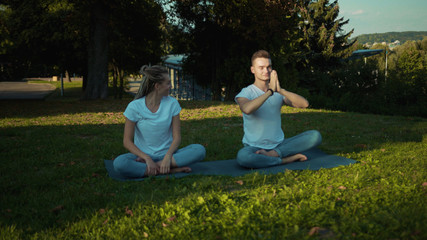 Close-up caucasian couple take a rest in the park practising yoga poses deep breathing cardio...