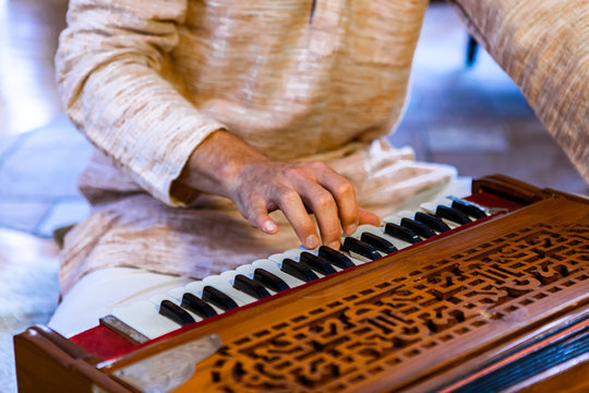 Closeup of shamanic male hands on harmonium keys playing sacred kirtan music for divine power and spiritual energy to connect with positive soul 