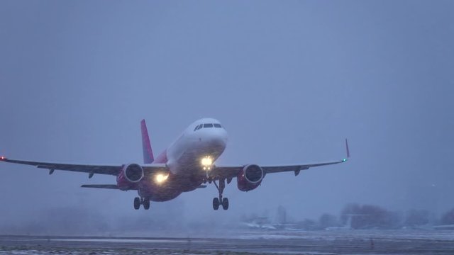 Airplane (aircraft) taking off in a heavy evening blizzard (snowstorm)