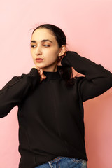 Portrait of a young and stylish middle-eastern woman in casual clothing. Attractive female posing in studio on bright background