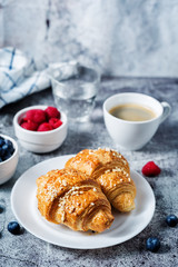 Fresh croissants with berries and cup of coffee