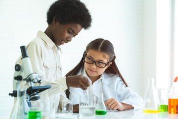 Asian school kid or scientist studying science AND experimenting with chemicals at laboratory.