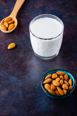 Almond milk with almond on dark background. Homemade organic almond milk in a glass for healthy breakfast. Vegan milk from almonds nuts on a sackcloth. Alternative milk. Top view. Copy space