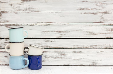 Enameled mugs in retro style on an old wooden background.