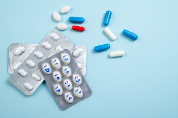 Blister of funny pills with smiles faces on blue background. Health care, daily pills, antidepressants, medicine, treatment concept. Copy space
