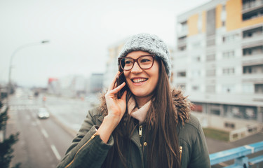 Fototapeta premium Young woman talking on smartphone. Smiling millennial girl talking on mobile phone