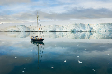 calm harbour with alone yacht and glacier in Antarctica