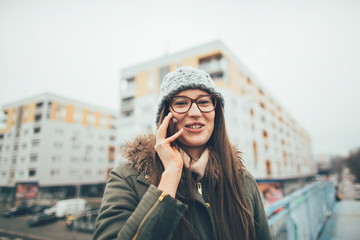 Fototapeta premium Smiling millennial girl talking on mobile phone outdoors