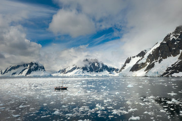 floating yacht in calm water of strait with icebergs