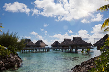 Wooden walkways over the water of the blue tropical sea to authentic traditional Polynesian thatched roof houses