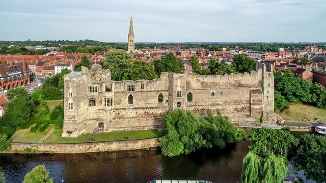 Ruins of medieval Gothic castle in Newark on Trent, near Nottingham, Nottinghamshire, England, UK. Aerial 4K approaching video with Trent River in sunset light