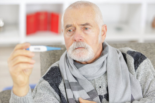 Senior Man Checking Body Temperature With Thermometer