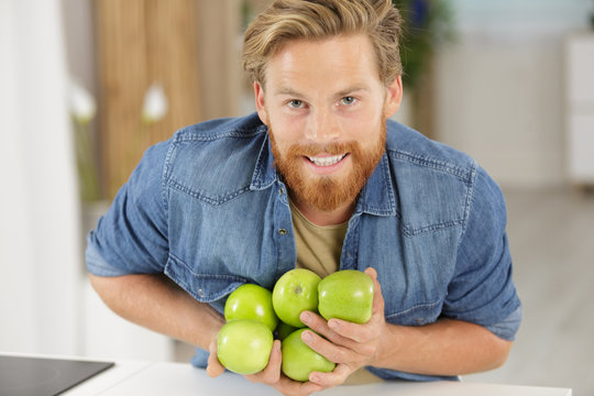 man dropping an armful of apples on to the worktop