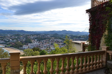 classical beauty: a balustrade, a wall twined with wild grapes, a beautiful city among the mountains and a cloudy sky above all