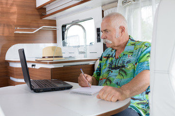 senior man using a laptop in a van