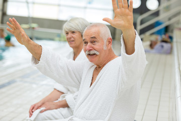 senior couple in bathrobe waving at someone