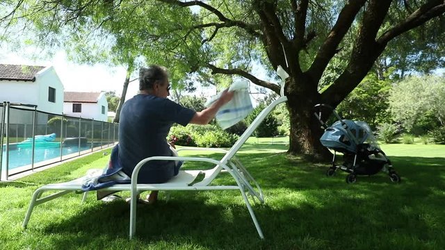 Casual Candid Senior Man Getting Up From Chair Outside In Backyard