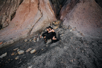 Asian couple in love hugs sitting on the rocks. Love story