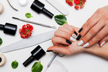 Matte black and white manicure on woman's hands. Tools for manicure. Flat lay