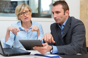 man and woman discussing over digital tablet in office